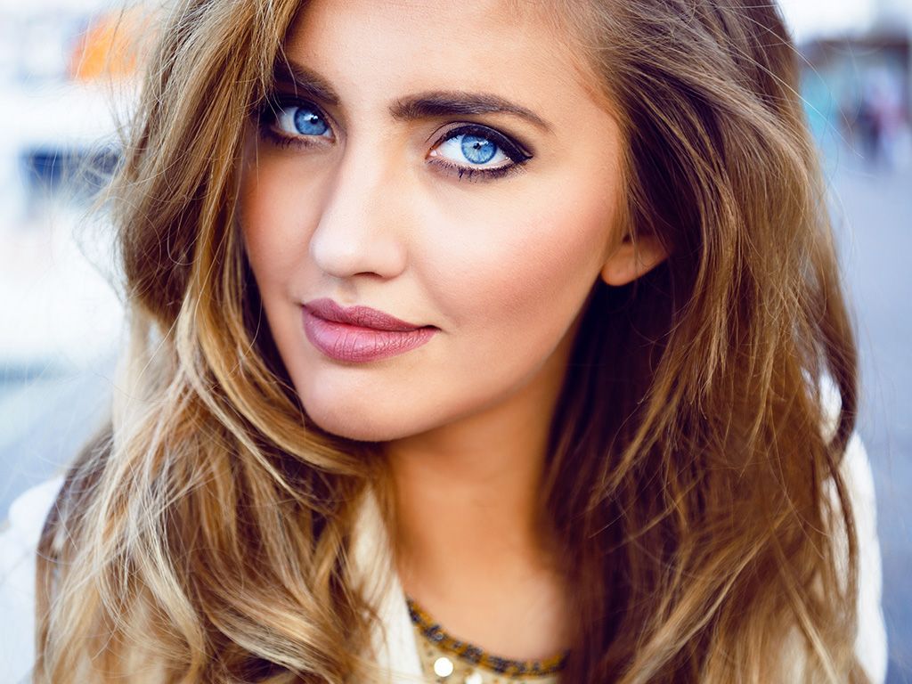Close up fashion portrait of seductive woman with big blue eyes ,full lips , prefect skin and long fluffy curled hairstyle.